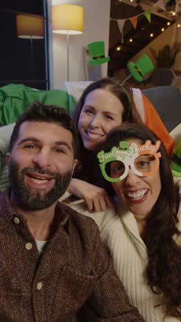 vertical video pov shot of friends dressing up at home celebrating at st patrick's day party making video call on mobile phone