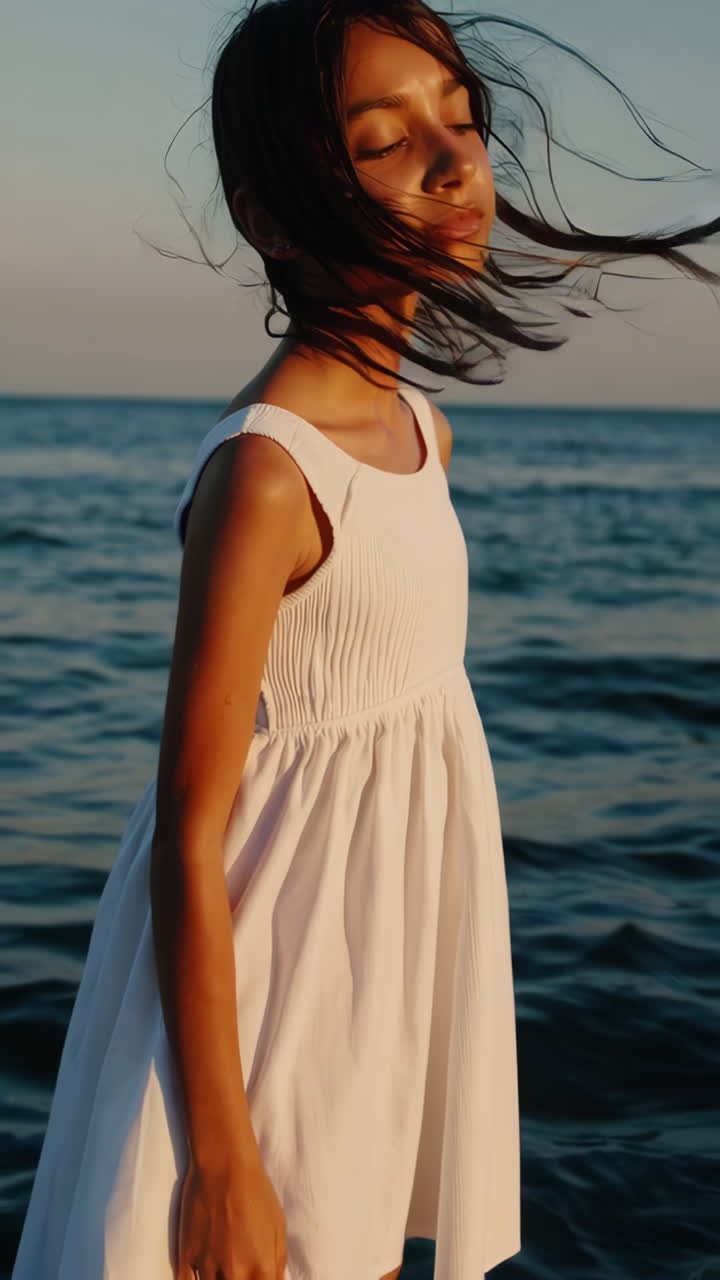 Woman in white dress standing in the sea at sunset