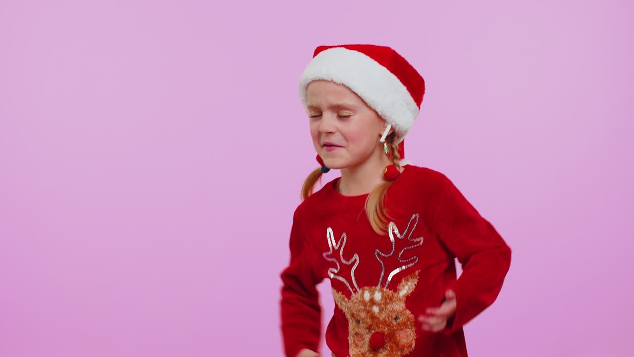 Girl in christmas sweater listening music via earphones dancing disco fooling around having fun