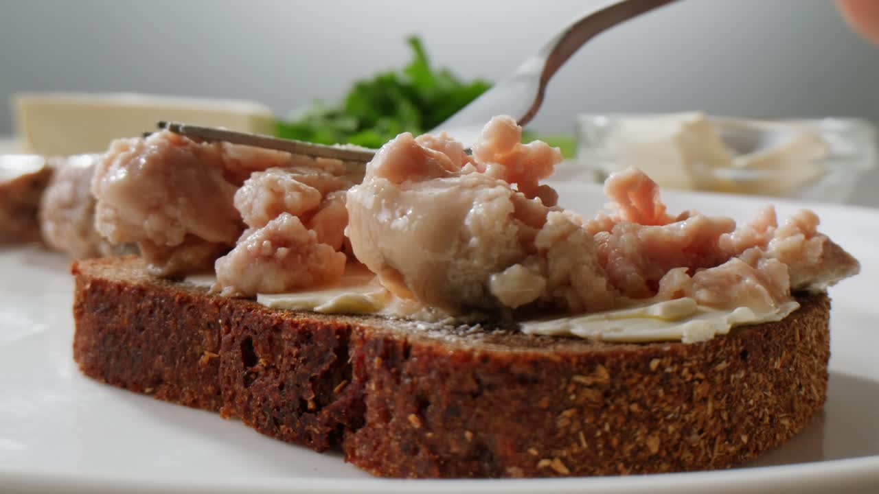 Smoked cod liver in oil in open tin can with fresh greens on wooden table. Seafoods delicacy. High quality 4k footage
