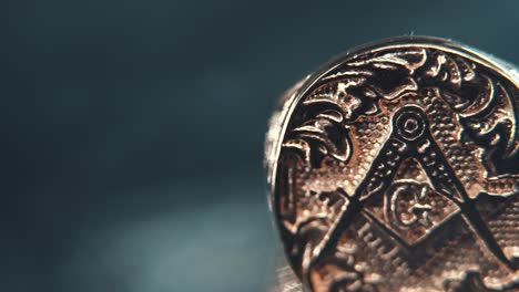 a macro detailed shot of a golden textured freemasons ring, on a rotating stand, mirror reflection, illuminati symbol, dark blurry baclground, professional studio lighting, 4k video