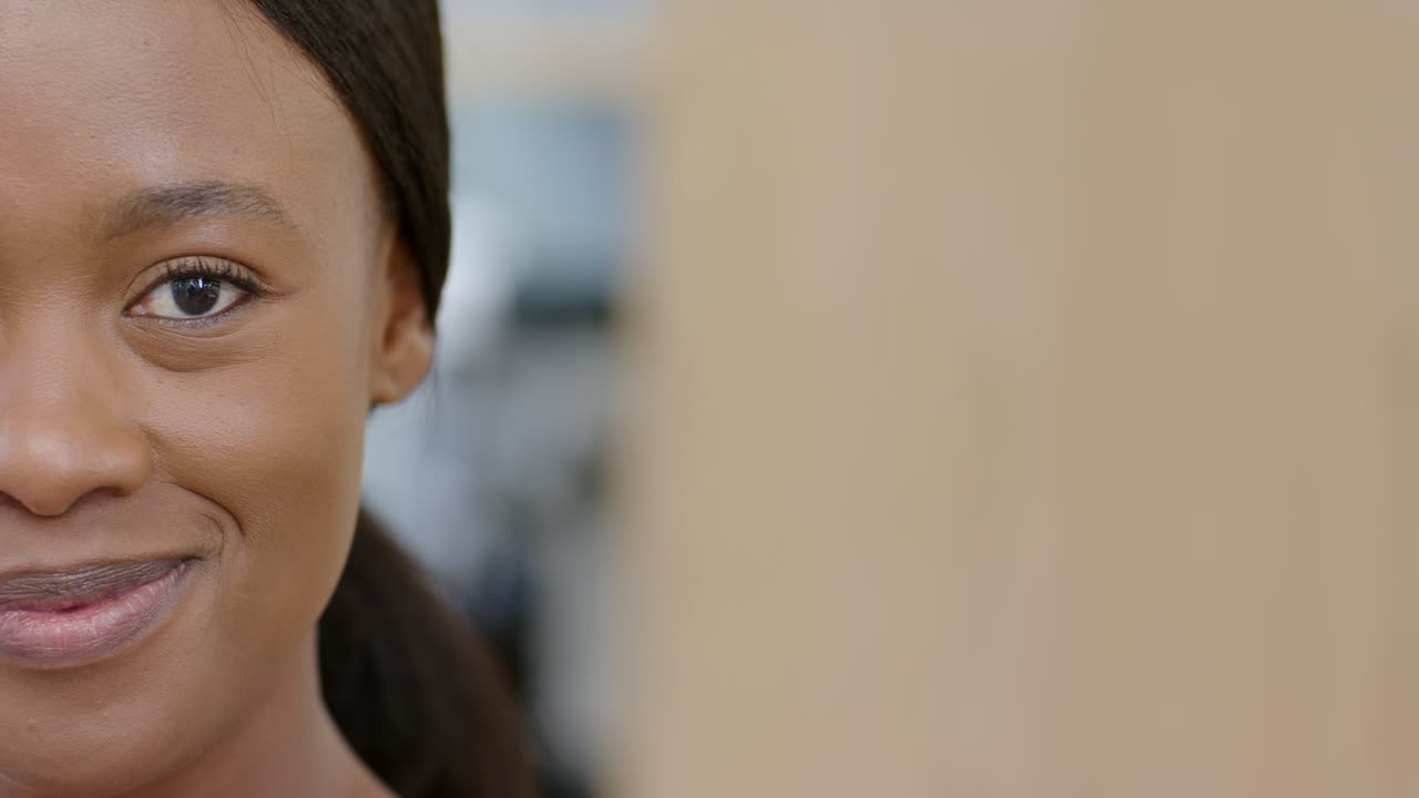Donna afroamericana con sguardo che si addolcisce in un sorriso allegro al lavoro, accanto a un pannello in legno, con spazio per il testo