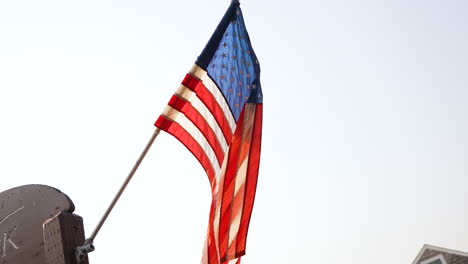 slow motion shot of an american flag flying in the wind off of a flag pole