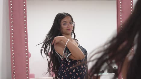 Young woman grooms her hair in front of vanity mirror, feeling confident and relaxed