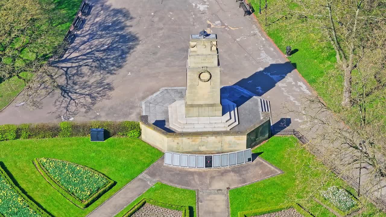 Drone above monument wide grassy lawns with visible paths, benches, and trees in Clifton Park War Memorial.