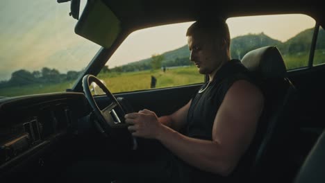 man using phone in vintage car at sunset