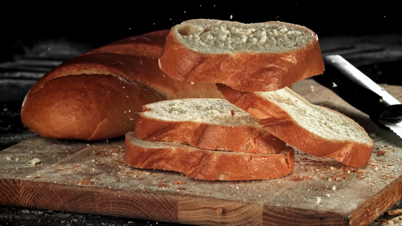 Movimento rallentato di fette di pane fresco che cadono su un tagliere di legno