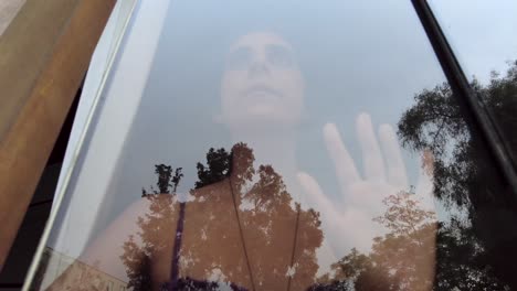 sad young woman behind a glass window, feeling trapped suffering from depression, lockdown