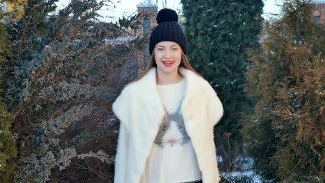 hermosa chica con labios rojos en abrigo blanco está dando vueltas en el fondo de abeto