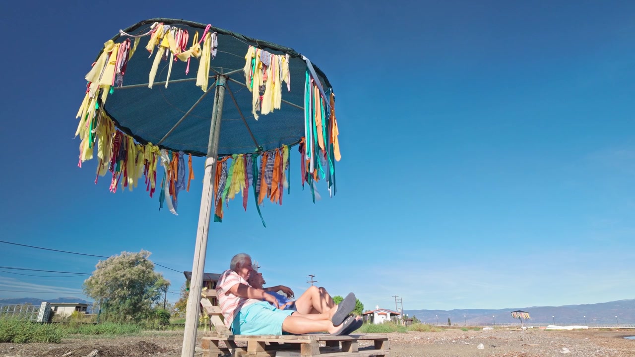 COPPIA IN VACANZA ECONOMICA CONDIVIDE UNA SDRAIO ECONOMICA E UN VECCHIO OMBRELLONE DA SPIAGGIA.