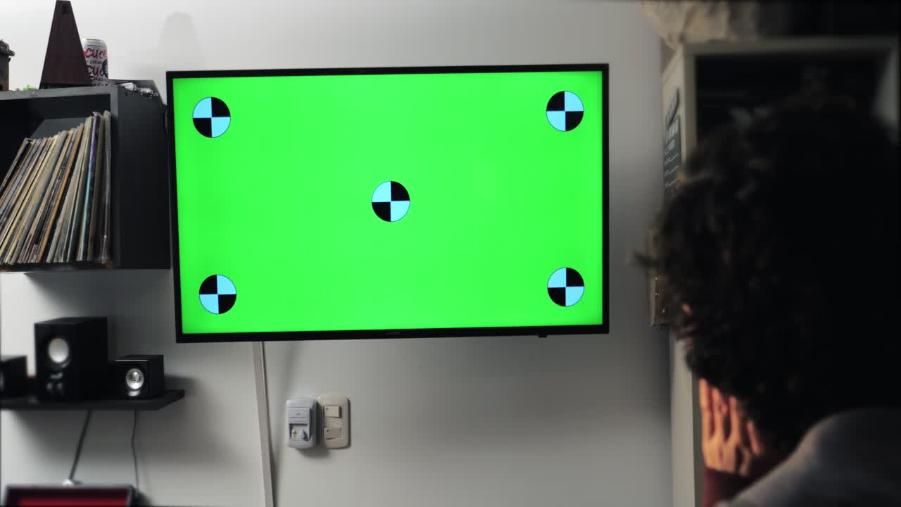 Person Watching Green Screen Television with Tracking Markers at Home