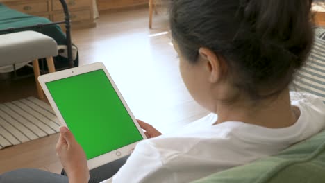 cinemagraph young woman holding digital tablet with green screen at home.