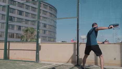 jugador de tenis de pádel golpea la pelota debajo de sus piernas después de que la pelota golpea la pared trasera