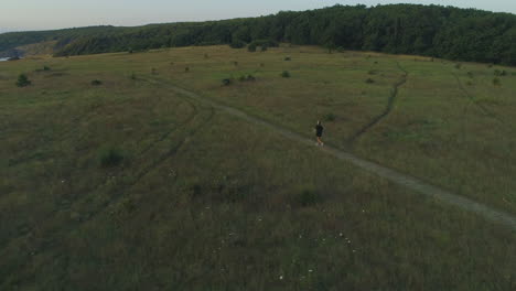 A-girl-walks-with-a-shovel-on-her-shoulders-in-a-meadow