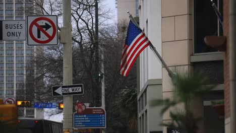 a slow-motion shot captures the american flag gently waving in the breeze, set against the backdrop of a bustling city skyline
