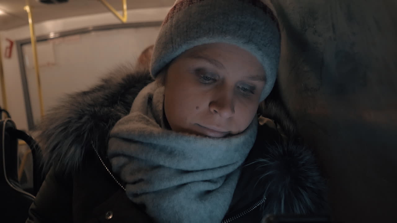 mujer tomando un autobús por la noche y usando el móvil