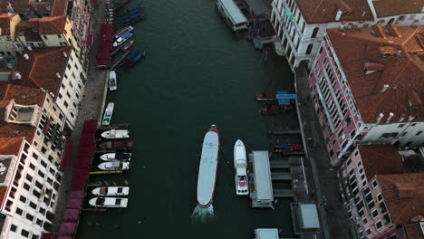 water bus traveling through the grand canal in venice at sunrise - aerial top down