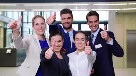 smiling businesspeople showing thumbs up in office