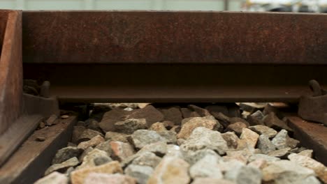 close-up panning shot of a rusty railroad track with details of bolts and stones