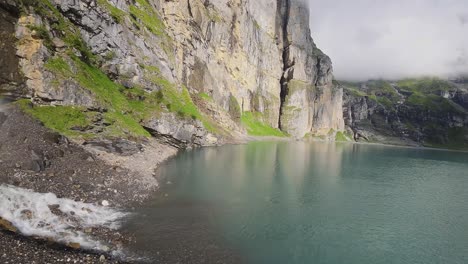 aerial flight next to a beautiful big waterfall on a mountain landscape, drone flying over a blue lake - oeschinen lake, switzerland