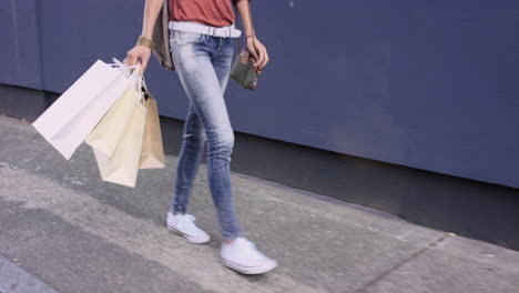 beautiful woman carrying shopping bags walking through city