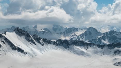 air flight through mountain clouds over beautiful snow-capped peaks of mountains and glaciers.