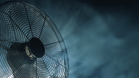 fan blades rotate in rays of light and fog. close-up shot