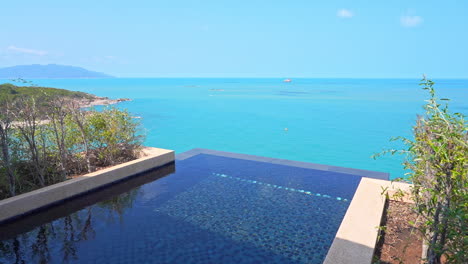 an oblique angle takes in the edge of a resort swimming pool to a view of the ocean and shoreline beyond