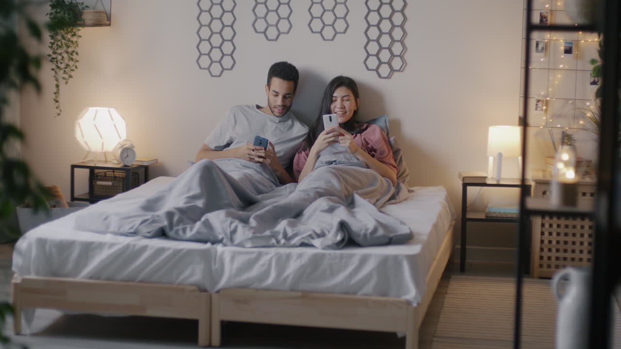 pareja usando teléfonos inteligentes en la cama