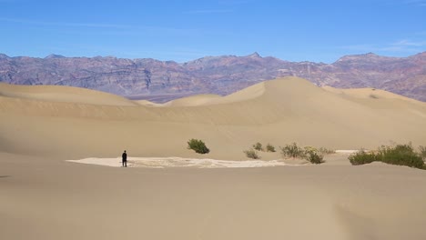 lonely person walking alone down a huge sand dune in the desert