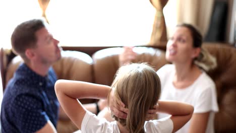 child covers ears during parents' argument