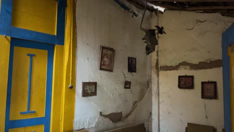 Dark,-empty,-scary,-interior-shot-of-old-home-with-family-photos-on-the-damaged-wall