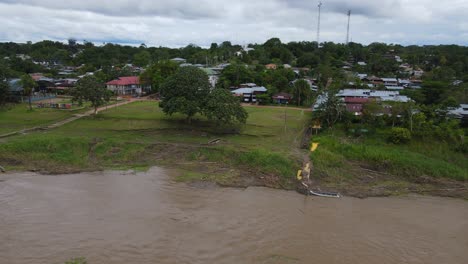 Luftaufnahme,-Die-Sich-Wegbewegt,-Malerischer-Blick-Auf-Eine-Blockhütte-Im-Amazonaswald-An-Einem-Hellen-Sonnigen-Tag-In-Kolumbien,-Amazonas-Im-Hintergrund