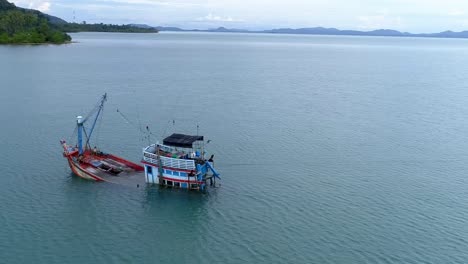 barco de pesca medio hundido en la orilla de una isla desierta orbit drone recortado