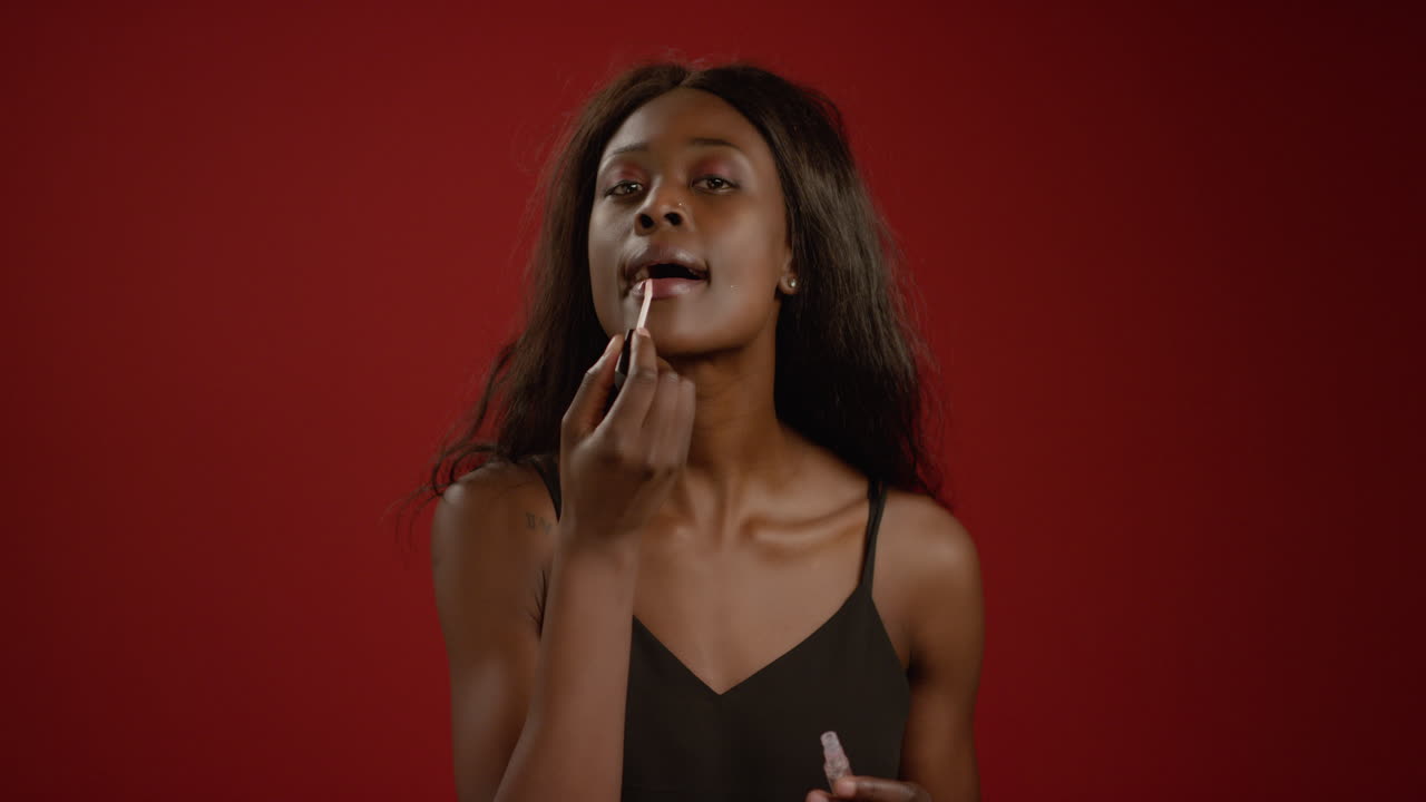 mujer joven pone brillo de labios