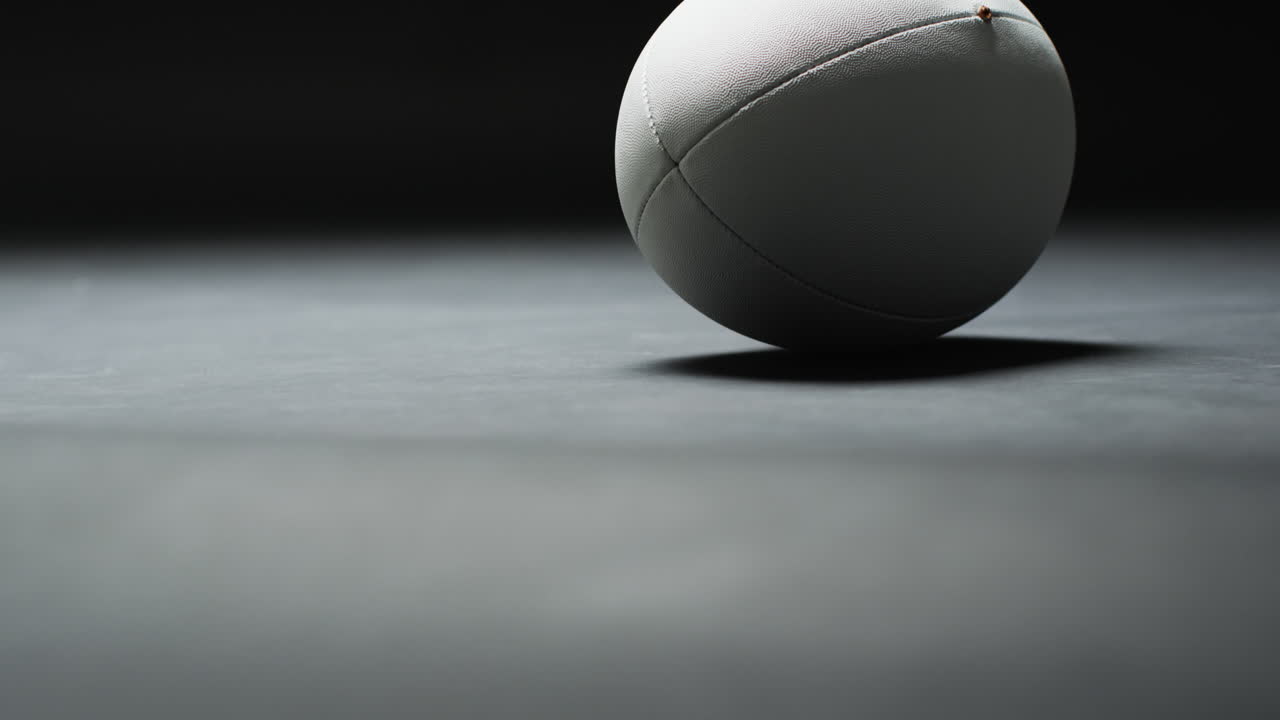 Ballon de rugby blanc sur fond sombre avec un espace pour le texte, au ralenti.