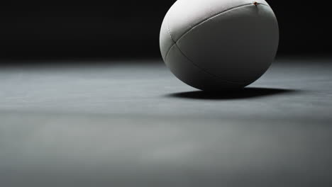 weißer rugbyball auf dunklem hintergrund mit kopierraum, zeitlupe