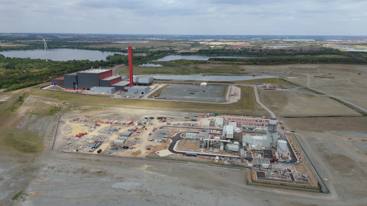 Aerial drone video of industrial power plant with chimney stacks, pylons, and energy generation using natural gas, coal, and oil in Bedford England UK