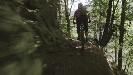 Close-up-of-young-woman-riding-her-mountain-bike-on-the-adrenaline-forest-track