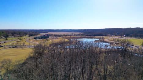 Flying-over-trees,-revealing-fishing-pond-and-Wilma-Rudolph-Event-Center-in-Clarksville-Tennessee