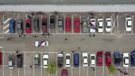 Vista-De-Arriba-Hacia-Abajo-De-Los-Coches-Y-Las-Personas-En-Un-Aparcamiento-En-Una-Reunión-De-Coches-Personalizados