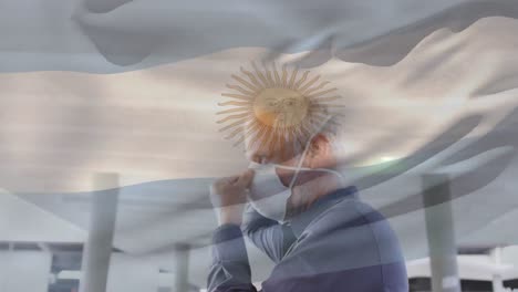 animation of flag of argentina waving over man wearing face mask during covid 19 pandemic