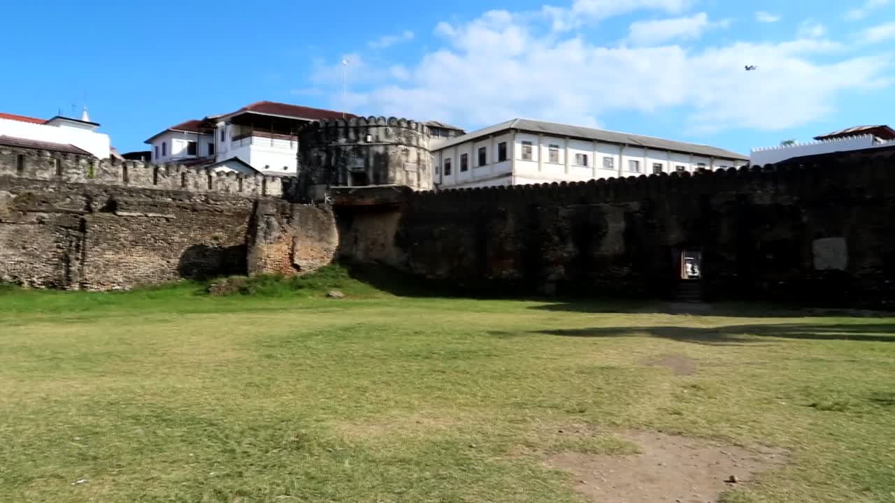 tiendas locales en el jardín de la antigua fortaleza de ngome kongwe con una mujer turista que aparece caminando