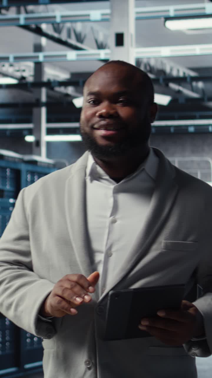 Vertical video Cheerful data center programmer using tablet to manage software updates