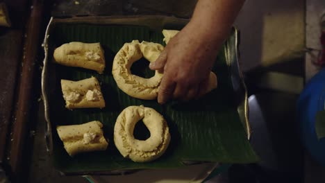 woman placing paraguayan chipa on a baking tray with banana leaves to prevent sticking while cooking in the tatakua, a traditional paraguayan clay oven