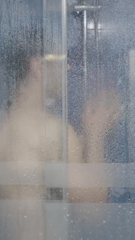 man showering behind a wet glass door