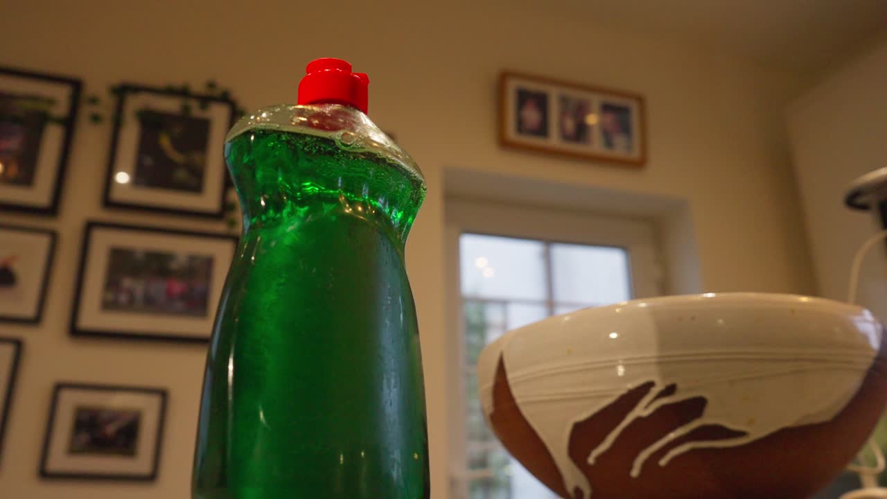 Cozy home zooms out from a green dish soap washing up bottle to reveal blur family pictures