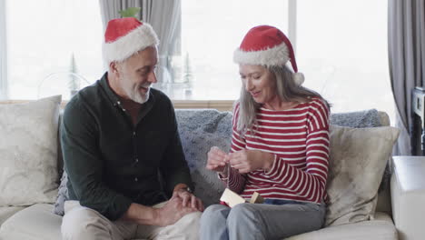 Pareja-Caucásica-De-Mediana-Edad-Con-Sombreros-De-Santa-Hablando-En-Navidad-En-Casa,-Cámara-Lenta