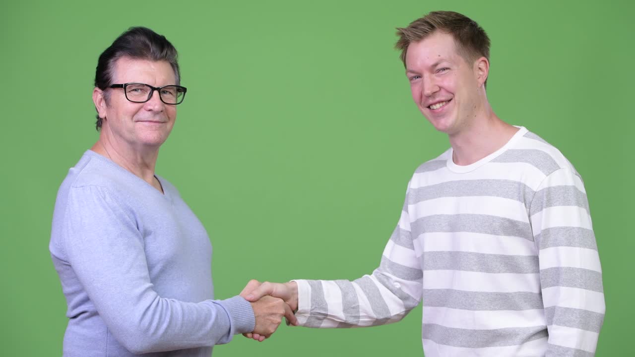 Senior handsome man and young handsome man shaking hands together
