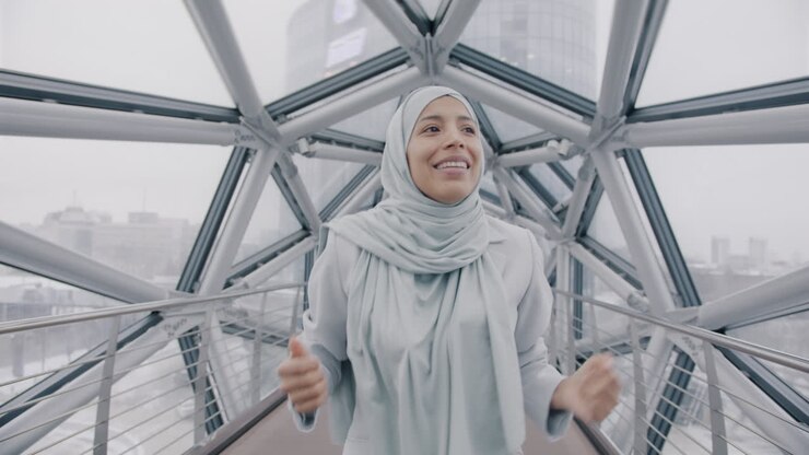 Donna gioiosa con hijab su un ponte moderno